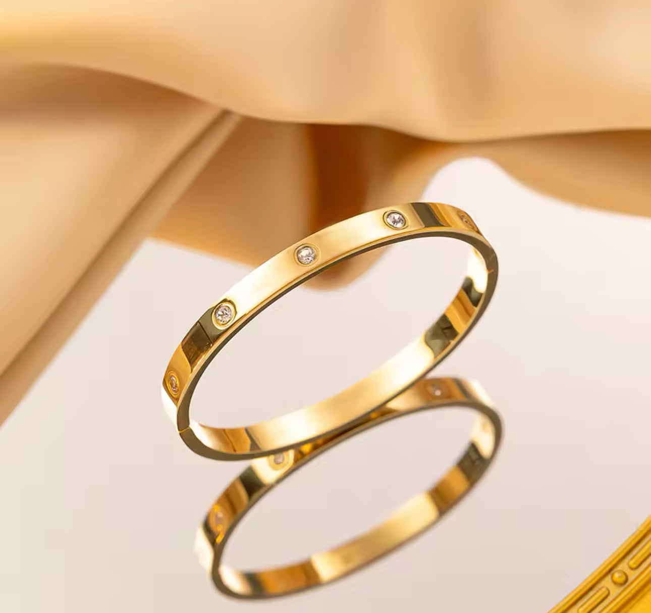 Close up view of elegant 18k Gold plated stainless steel, Cartier dupe, designer inspired, classic bangle bracelet with a smooth, polished finish and inlay crystals, designed with a lightweight and tarnish resistant material for timeless sophistication.