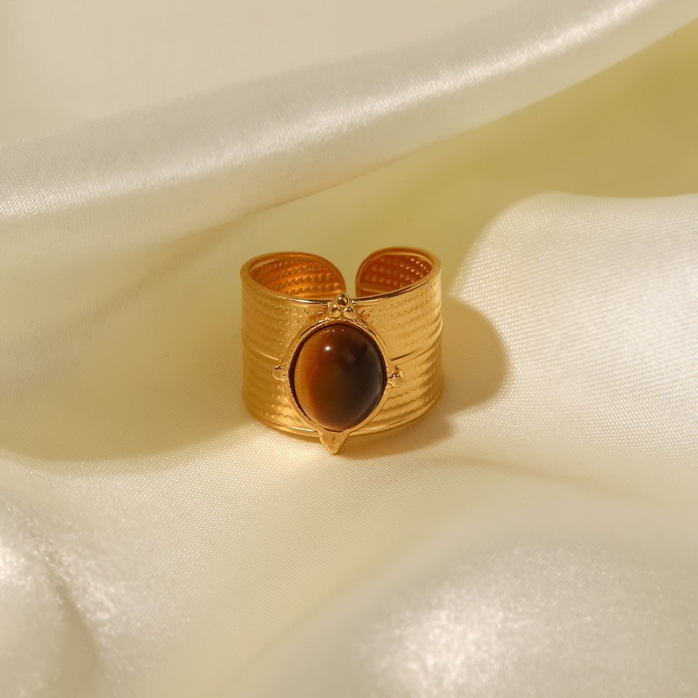 Front view of bold statement ring that features a striking tiger's eye center stone set in a luxurious gold-plated, tarnish resistant, long lasting stainless steel band. The thick adjustable band adds a touch of drama, making it the perfect accessory for those who dare to stand out.